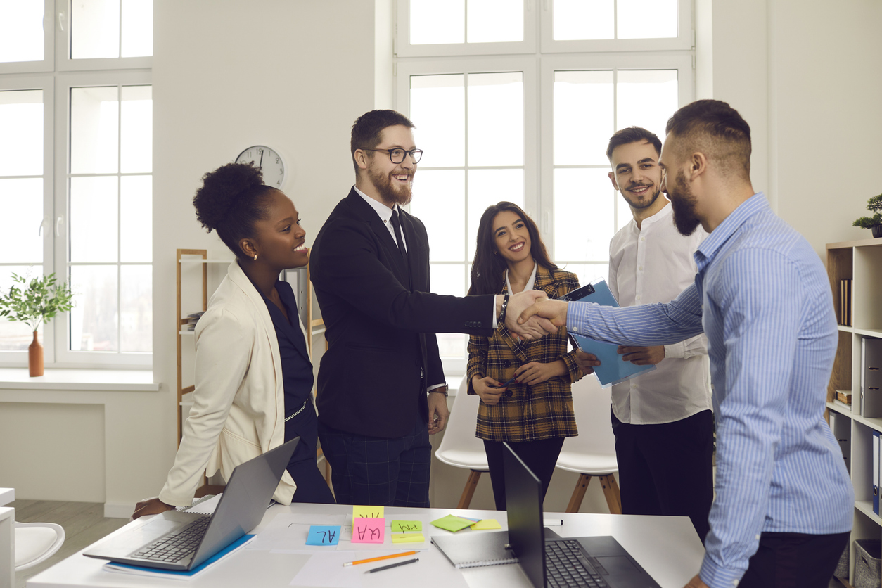 The Essential Guide to Effective Onboarding Strategies for New Hires 3 Male leader of a business team greets a new team member shaking his hand.